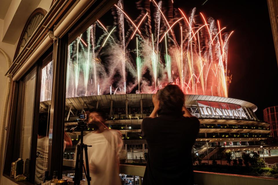 People watch and record videos as fireworks go off around the Olympic Stadium during the closing ceremony of the Tokyo 2020 Olympic Games, in Tokyo, on August 8, 2021. (Photo by Yasuyoshi CHIBA / AFP) (Photo by YASUYOSHI CHIBA/AFP via Getty Images)