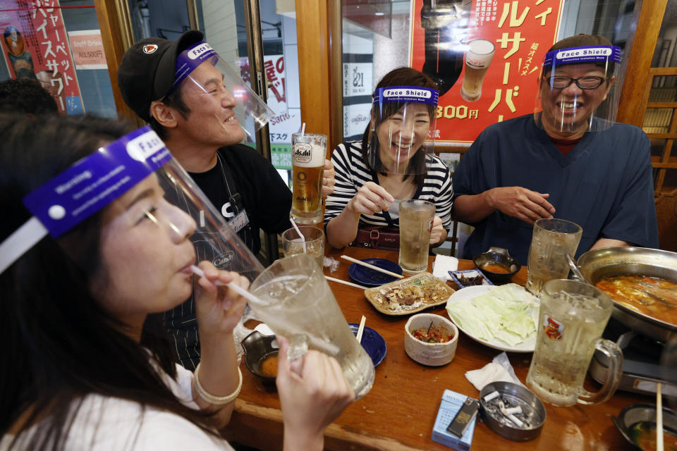 People wearing face shield, eat together at a pub in Osaka, western Japan Monday, May 25, 2020 as Japan has lifted the coronavirus state of emergency in Osaka and the two neighboring prefectures of Kyoto and Hyogo. (Suo Takekuma/Kyodo News via AP)