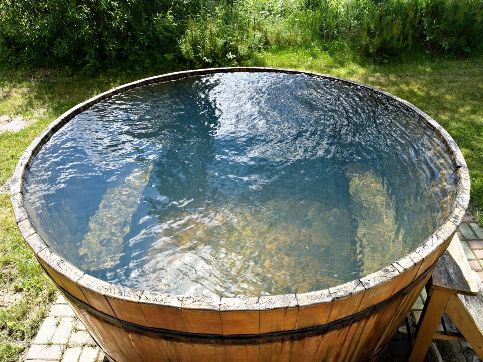 wooden cold-plunge pool on a brick patio in a backyard