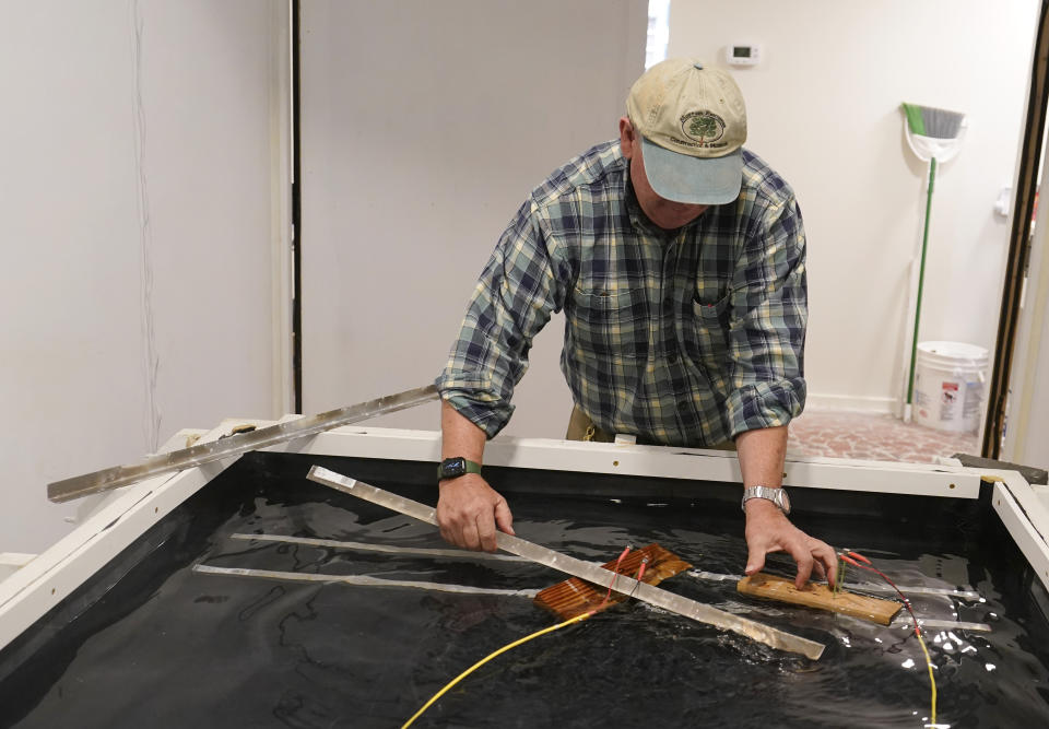 Co owner of Building Resilient Solutions, Kerry Shackelford hooks up pine boards that are used to test flood resistance at his lab Tuesday, Oct. 4, 2022, in Suffolk , Va. Whenever historic homes get flooded, building contractors often feel compelled by government regulations to rip out the water-logged wood flooring, tear down the old plaster walls and install new, flood-resistant materials. But Virginia restorers Paige Pollard and Kerry Shackelford say they can prove that historic building materials can often withstand repeated flooding. (AP Photo/Steve Helber)