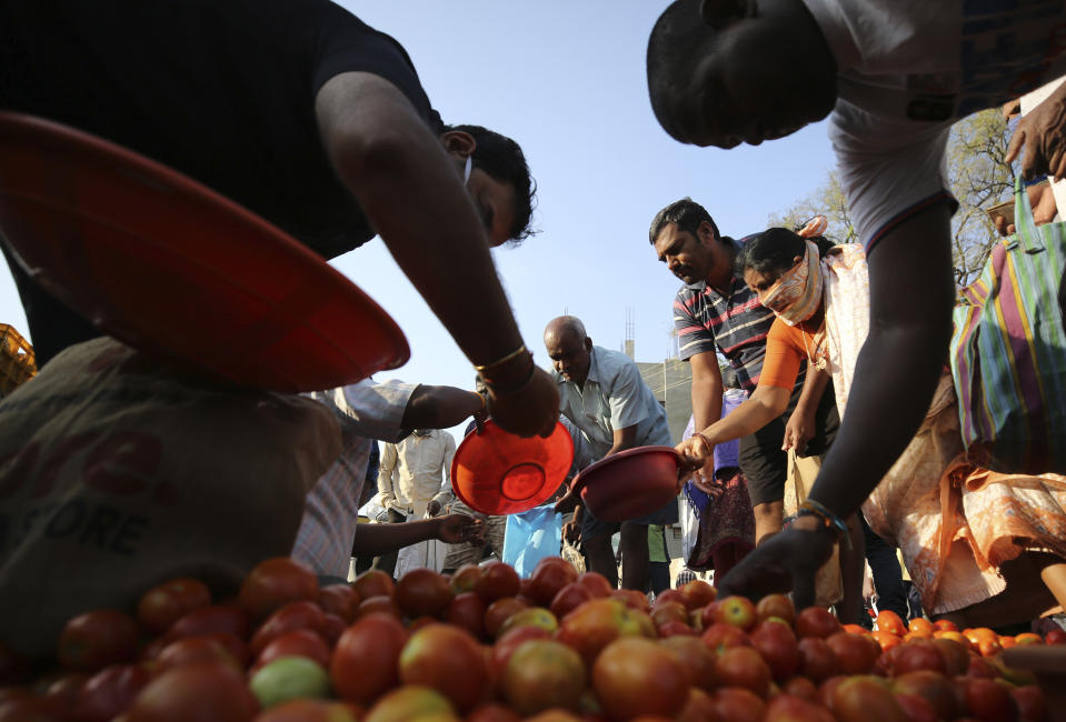 Indians buy vegetables during lockdown in Bangalore, India, Thursday, March 26, 2020. The unprecedented lockdown keeping India's 1.3 billion people at home for all but essential trips to places like supermarkets or pharmacies is meant to keep virus cases from surging above the 553 already recorded and overwhelming an already strained health care system. The new coronavirus causes mild or moderate symptoms for most people, but for some, especially older adults and people with existing health problems, it can cause more severe illness or death. (AP Photo/Aijaz Rahi)