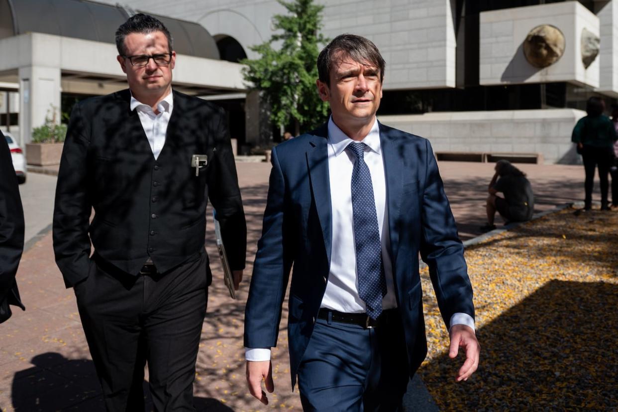 Cameron Jay Ortis, right, a former RCMP intelligence director accused of disclosing classified information, leaves the Ottawa Courthouse following a break in proceedings in Ottawa on Tuesday, Oct. 3, 2023. (Spencer Colby/The Canadian Press - image credit)