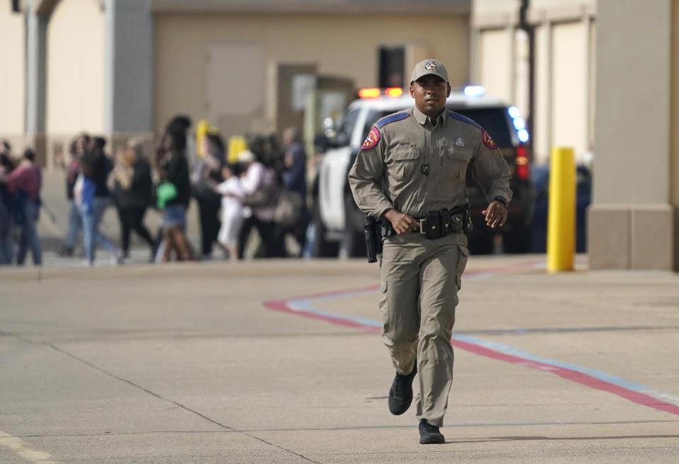 A law enforcement officer runs as people are evacuated from a shopping center where a shooting occurred Saturday, May 6, 2023, in Allen, Texas. (AP Photo/LM Otero)