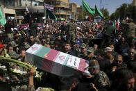 Mourners carry a flag-draped casket during a mass funeral for victims of Saturday's terror attack on a military parade, in the southwestern city of Ahvaz, Iran, Monday, Sept. 24, 2018. Thousands of mourners gathered at the Sarallah Mosque on Ahvaz's Taleghani junction, carrying caskets in the sweltering heat. (AP Photo/Ebrahim Noroozi)