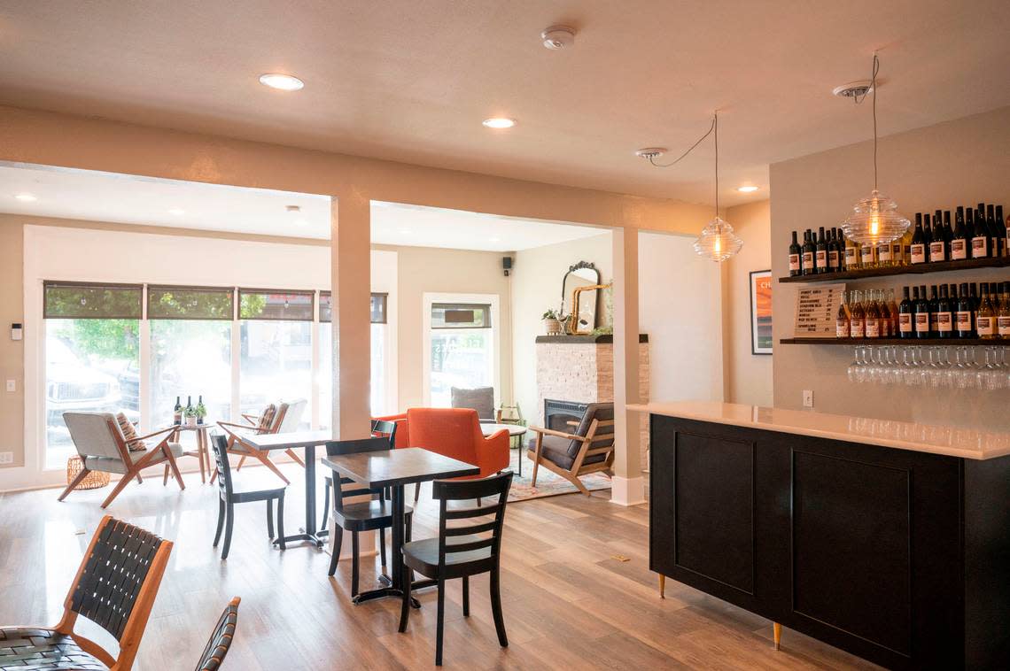 Dahlman Cellars tasting room in Tacoma features a small pour bar and four seating areas, including the Living Room with a couch and coffee table and the Fireplace Room with four lounge chairs.