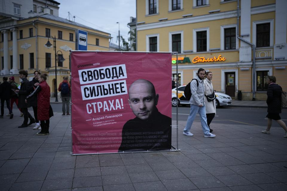 People walk past an election poster with a portrait of jailed Andrei Pivovarov, the leader of the Open Russia opposition group financed by Russian tycoon Mikhail Khodorkovsky, and words "Freedom is stronger than fear!" in Moscow, Russia, Tuesday, Sept. 7, 2021. Pivovarov, who had planned run for the Duma, was removed from a Warsaw-bound plane just before takeoff from St. Petersburg and taken to the southern city of Krasnodar. He was accused of supporting a local candidate last year on behalf of an “undesirable” organization and jailed pending an investigation. (AP Photo/Alexander Zemlianichenko)