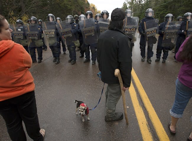 Protesters face a line of police officers in Rexton, N.B. as police began enforcing an injunction to end an ongoing demonstration against shale gas exploration in eastern New Brunswick on Thursday, Oct.17, 2013. Police say at least five RCMP vehicles were destroyed after they were set ablaze and at least one shot was fired by someone other than a police officer at the site of the protest in Rexton.THE CANADIAN PRESS/Andrew Vaughan