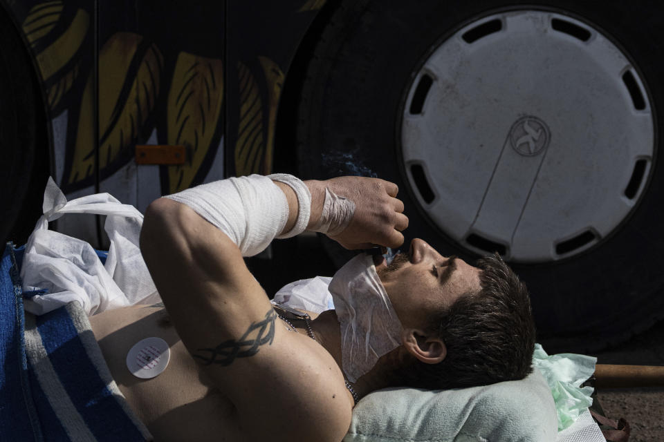 Oleksandr, an injured Ukrainian soldier, smokes a cigarette before evacuation by volunteers of the Hospitallers paramedic organisation near a special medical bus in Donetsk region, Ukraine, Wednesday, March 22, 2023. (AP Photo/Evgeniy Maloletka)