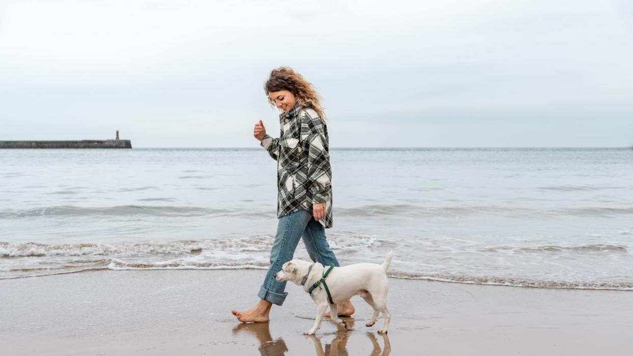 Woman walking on beach with her dog