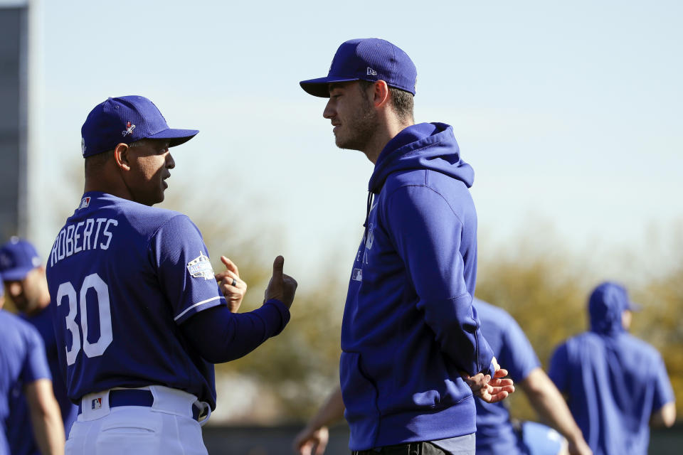 Los Angeles Dodgers manager Dave Roberts, left, talks with center fielder Cody Bellinger during spring training baseball Friday, Feb. 14, 2020, in Phoenix. (AP Photo/Gregory Bull)