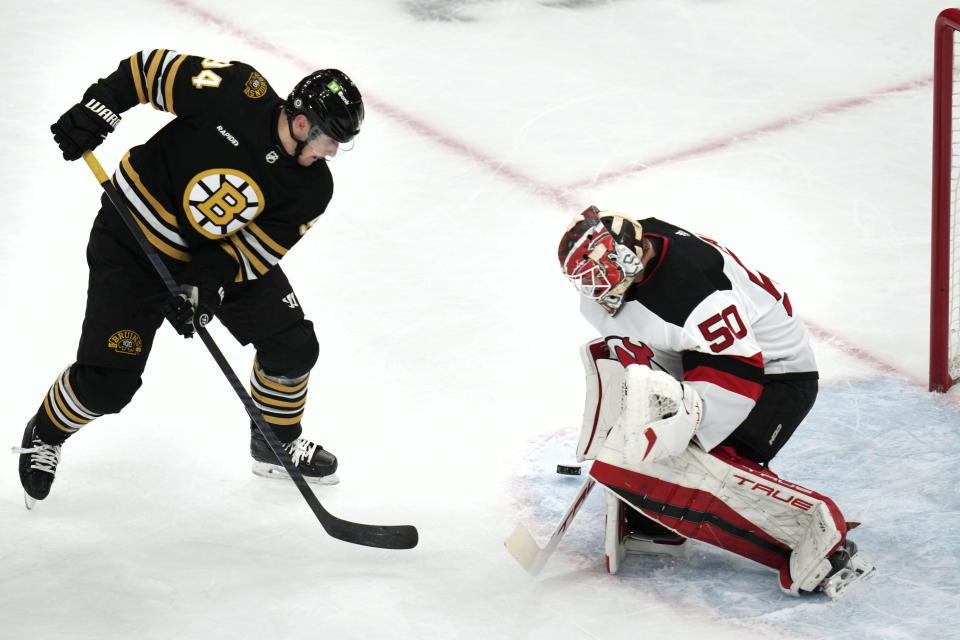 New Jersey Devils goaltender Nico Daws (50) makes a save on a shot by Boston Bruins center Jakub Lauko, left, during the first period of an NHL hockey game, Monday, Jan. 15, 2024, in Boston. (AP Photo/Charles Krupa)