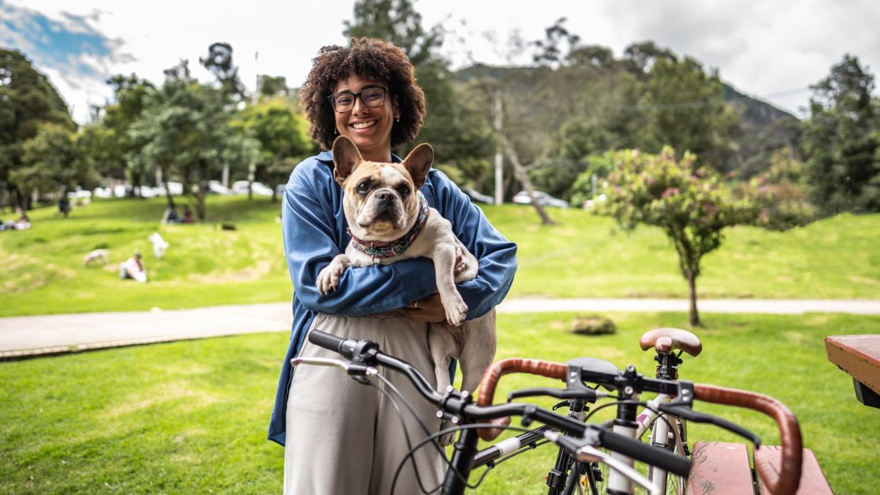  Young woman holding dog in her arms at the park 