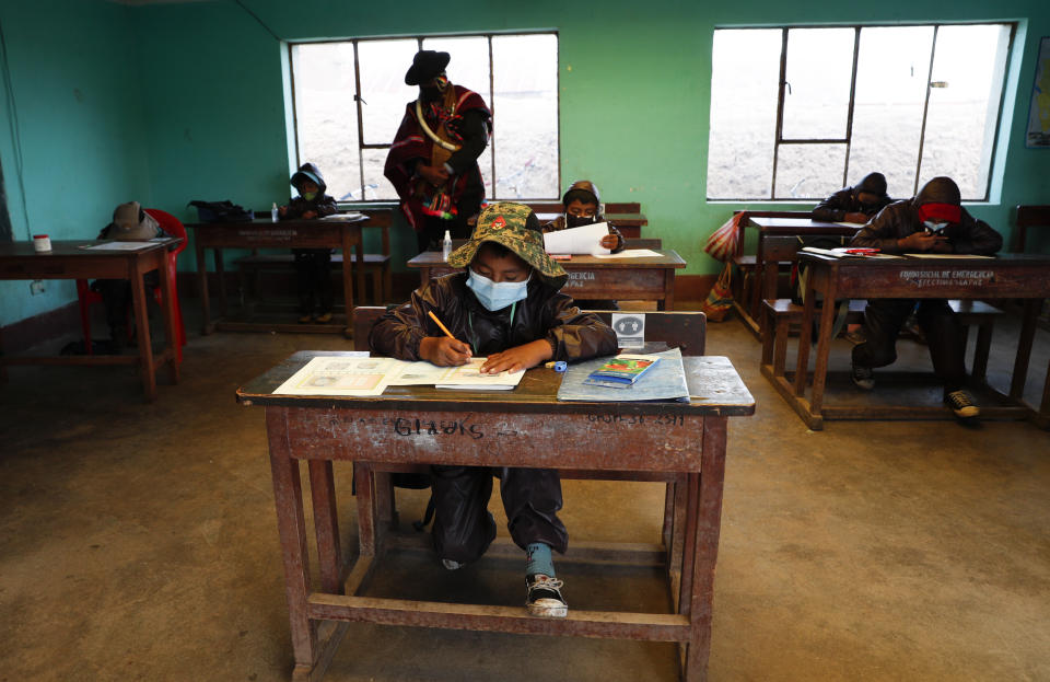 An Aymara Indigenous parent watches over students during the first week back to in-person classes with pupils wearing new protective uniforms amid the COVID-19 pandemic near Jesus de Machaca, Bolivia, Thursday, Feb. 4, 2021. (AP Photo/Juan Karita)