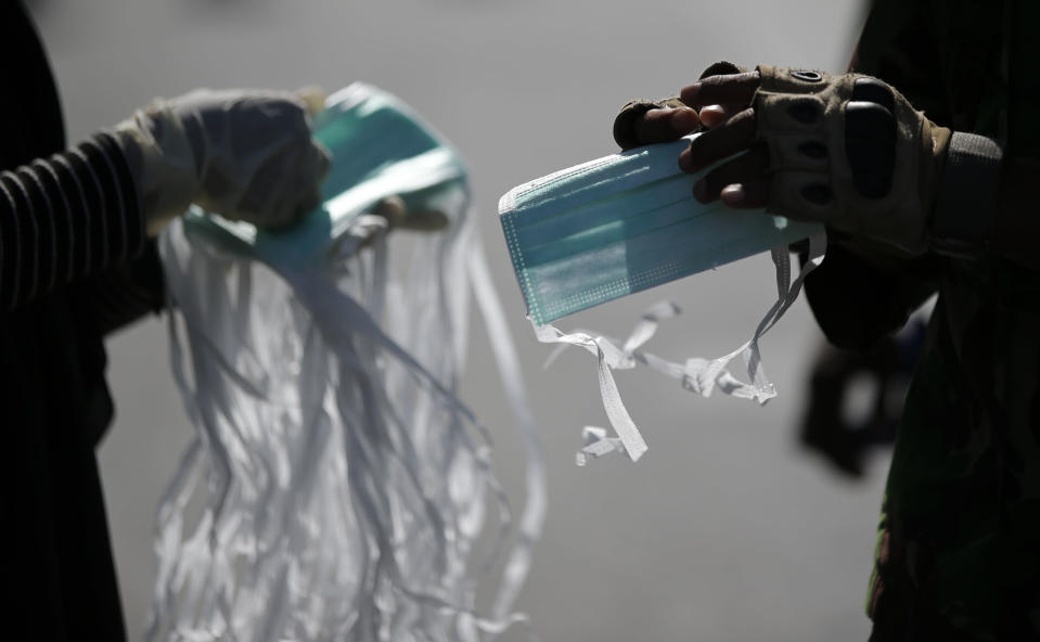 In this Saturday, Oct. 6, 2018, file photo, a volunteer hands over face masks to rescuers as recovery efforts continue at the earthquake-hit Balaroa neighborhood in Palu, Central Sulawesi, Indonesia. (AP Photo/Aaron Favila, File)