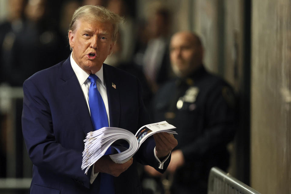 Former President Donald Trump speaks with the media while holding news clippings following his trial at Manhattan criminal court in New York on Thursday, April 18, 2024. (Brendan McDermid/Pool Photo via AP)