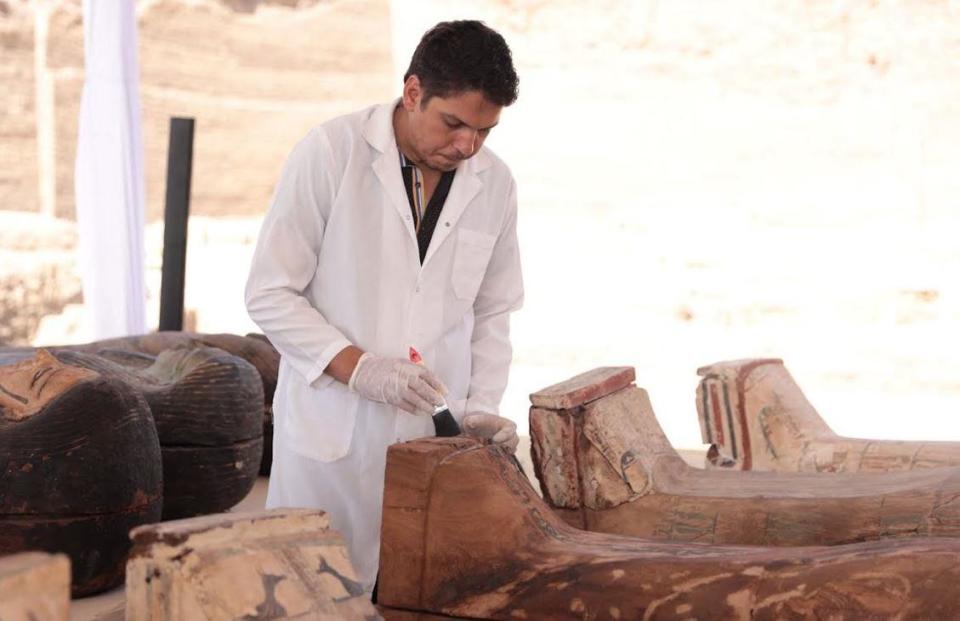 An archaeologist cleans a sarcophogus, or coffin, still sealed and containing the mummified remains of an ancient Egyptian, as artifacts are displayed at the Saqqara Necropolis near Cairo, Egypt, in a photo provided by the Egyptian Ministry of Antiquities, May 30, 2022.  / Credit: Egyptian Ministry of Tourism and Antiquities