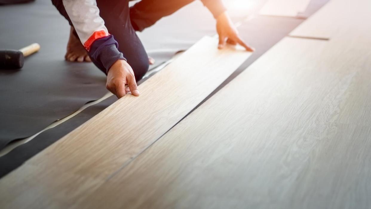 Worker installing new vinyl laminate floor tile