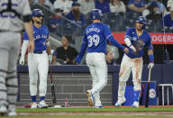 Toronto Blue Jays' Kevin Kiermaier (39) is congratulated by teammates Bo Bichette, second from left, and Justin Turner, right, after scoring on a Vladimir Guerrero Jr. single during third-inning baseball game action against Colorado Rockies pitcher Kyle Freeland in Toronto, Sunday, April 14, 2024. (Frank Gunn/The Canadian Press via AP)