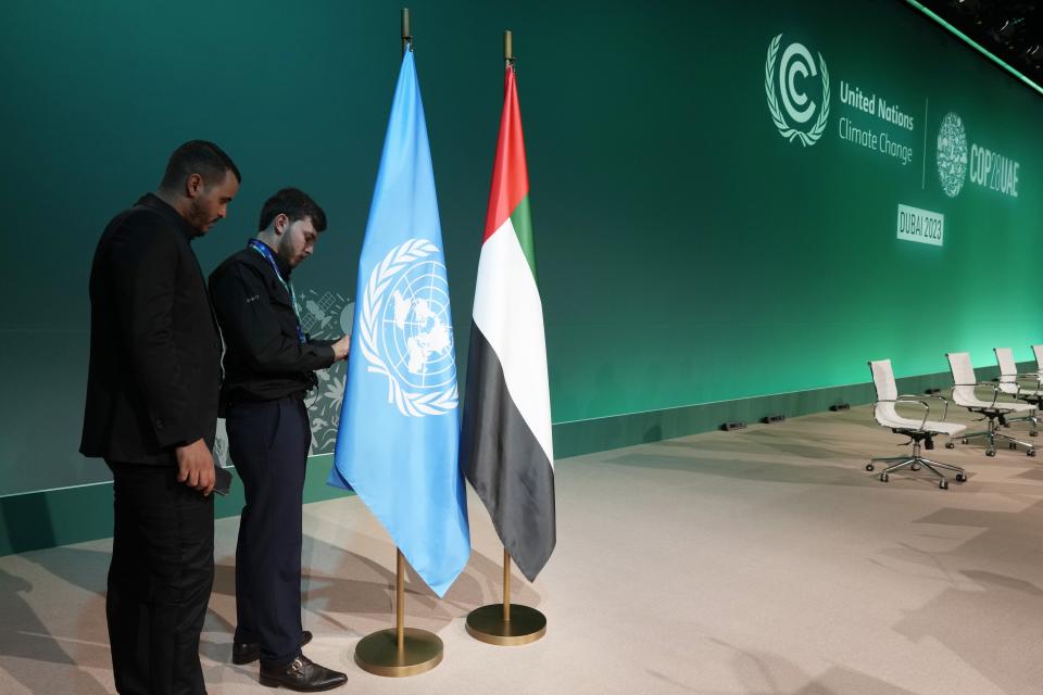 People adjust the flags for the United Arab Emirates and the United Nations at the plenary ahead of the COP28 U.N. Climate Summit, Tuesday, Nov. 28, 2023, in Dubai, United Arab Emirates. (AP Photo/Peter Dejong)