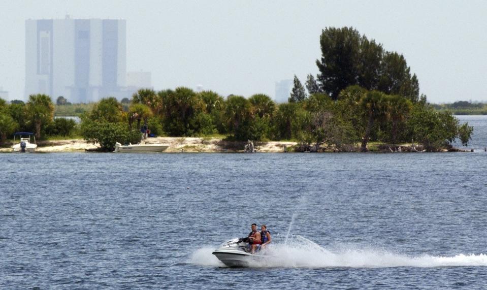 -The Vehicle Assembly Building at Kennedy Space Center can be seen in the background Wednesday as personal-watercraft riders head north along the Indian River Lagoon in Titusville.-