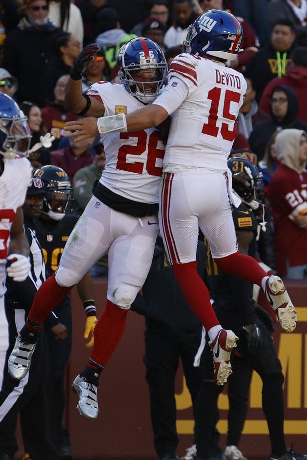 Giants RB Saquon Barkley (26) and QB Tommy DeVito (15) celebrate after connecting on a touchdown pass against the Washington Commanders during the first quarter at FedEx Field on Nov. 19, 2023.