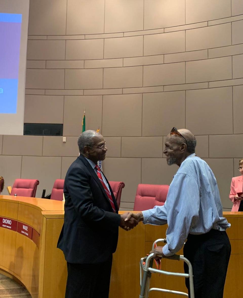 Mecklenburg County Commissioner Arthur Griffin shakes hands with Harvey Boyd, designer of the Mecklenburg County seal on May 16, 2023. The Board of County Commissioners inducted Boyd into the Order of the Hornet, the county’s most prestigious award.