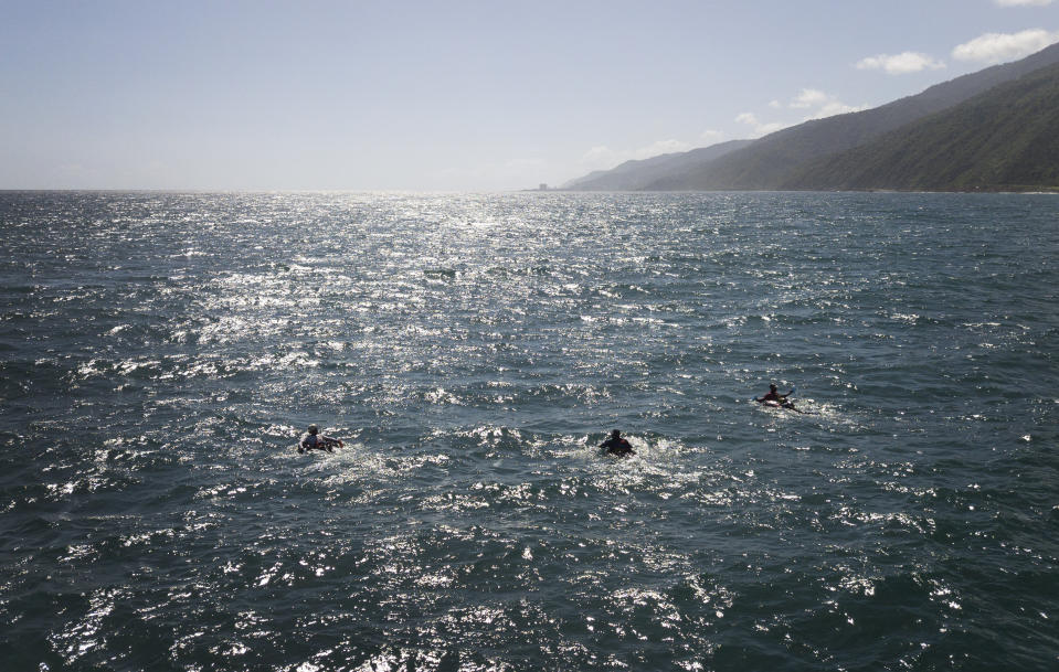 A group of bricklayers by trade float on their inner tubes in fishing in the open sea to fish at Playa Escondida in La Guaira, Venezuela, Friday, Aug. 14, 2020. Venezuelans desperate to feed their families amid the coronavirus pandemic are heading out to the open sea on inner tubes armed with a hook and line. It’s a risk they’re forced to take as the nationwide lockdown paralyzes an already failing economy and eliminates their jobs in construction and restaurants. (AP Photo/Matias Delacroix)