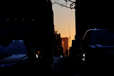 A pedestrian crosses a street on a frigid morning as the sun rises in New York, U.S., January 3, 2018. REUTERS/Lucas Jackson