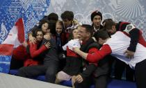 Meagan Duhamel and Eric Radford of Canada are hugged by their team in the "kiss and cry" area during the Team Pairs Short Program at the Sochi 2014 Winter Olympics, February 6, 2014. REUTERS/Darron Cummings/Pool