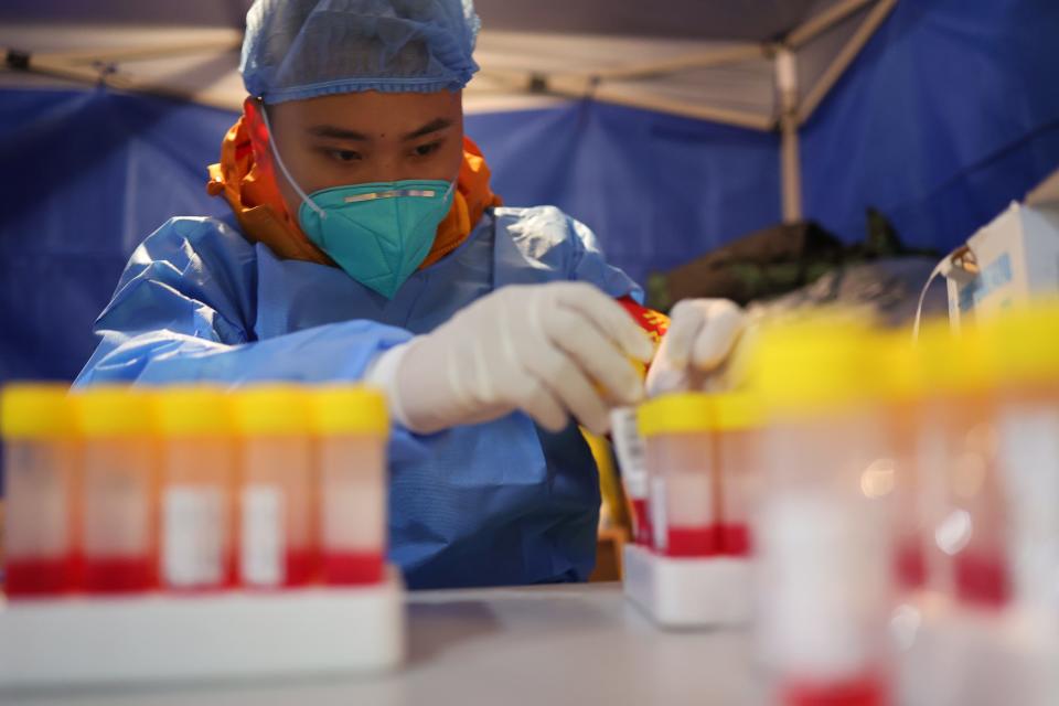 A volunteer prepares to collect swab samples from residents for COVID-19 nucleic acid testing at a gated community on November 16, 2022 in Chongqing, China.