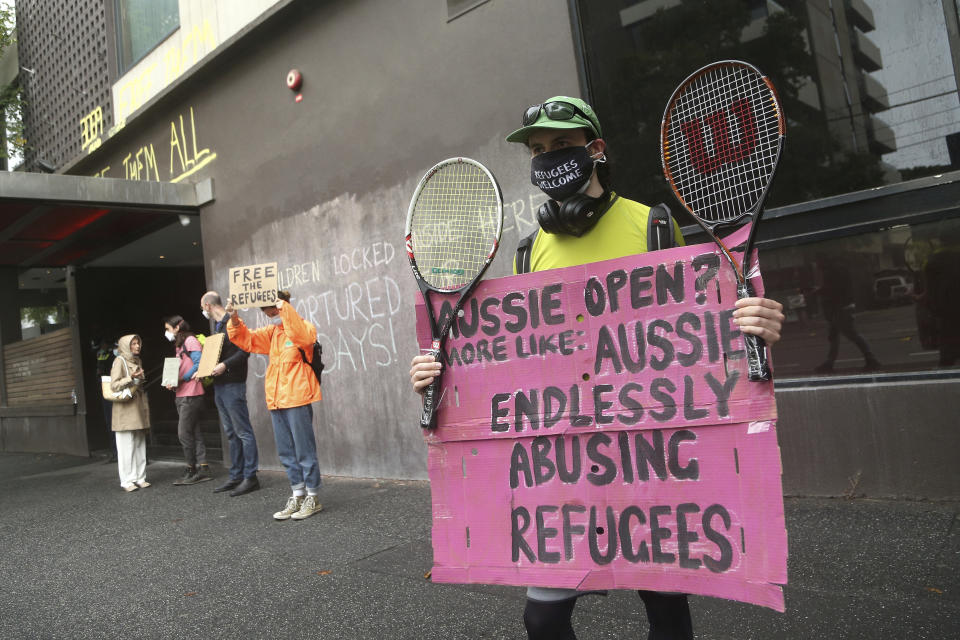 Protesters hold banners outside the Park Hotel calling for the release of refugees being detained inside in Melbourne, Australia, Saturday, Jan. 8, 2022. The world’s No. 1-ranked tennis player Novak Djokovic is also being held there after border officials canceled his visa last week over a vaccine requirement. (AP Photo/Hamish Blair)