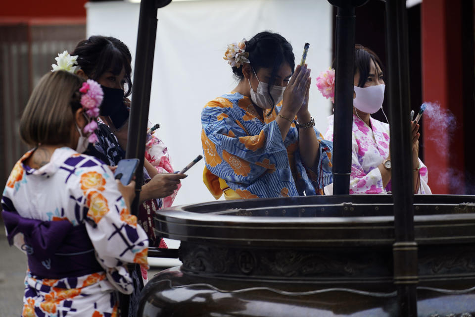 A restaurant employee wearing a protective face mask to help curb the spread of the coronavirus offer a joss sticks on a huge incense burner in the Asakusa district in Tokyo Monday, July 27, 2020. The Japanese capital confirmed Monday more than 100 new coronavirus cases. (AP Photo/Eugene Hoshiko)