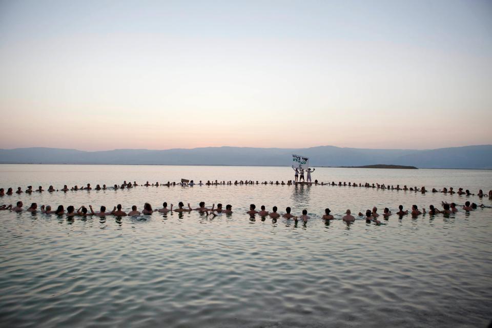 Environmental and social activists from Israel and around the world gather at the Dead Sea for a protest float against the deterioration of the sea's condition, in Israel, Friday, Sept. 14, 2012. The float was led by Tunick to protest the disappearance of the beach.