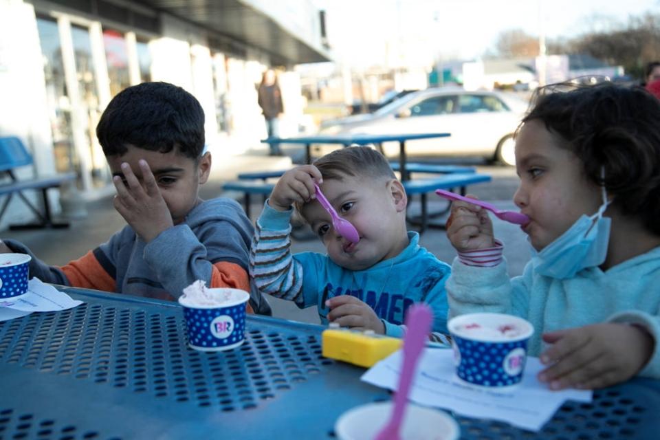 Siblings Sanaullah Khan, Mirwais Khan and Zahra Zadran eat ice cream (Reuters)