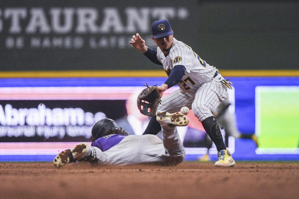 Colorado Rockies' Brendan Rodgers slides to second base against Milwaukee Brewers shortstop Willy Adames for a double during the ninth inning of a baseball game Saturday, July 23, 2022, in Milwaukee. (AP Photo/Kenny Yoo)