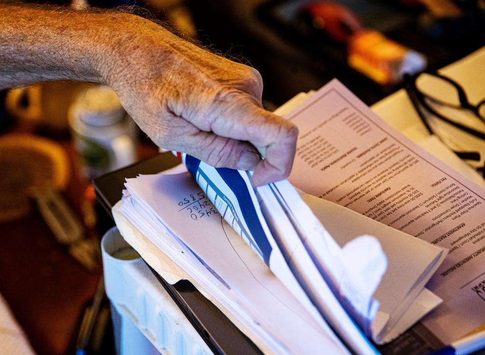 Todd Murray browses through rental property documents at his Naples duplex he shares with his brother Tommas on Tuesday, June 7, 2022. They say the duplex has been sold and that they have to be out by July 31. Tommas is on disability and Todd has a full time job at a local market. They say they can't afford another place to live because the rents are too high and the ones they can afford don't take pets. Tommas has a cat. They are afraid that they may become homeless.