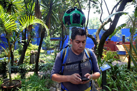 A Google employee, armed with a specialized Street view 360 degree camera, documents the garden at the childhood home of Mexican artist Frida Kahlo, now Frida Kahlo Museum, also known as "Casa Azul", in Mexico City, Mexico May 21, 2018. Picture taken May 21, 2018. REUTERS/Gustavo Graf