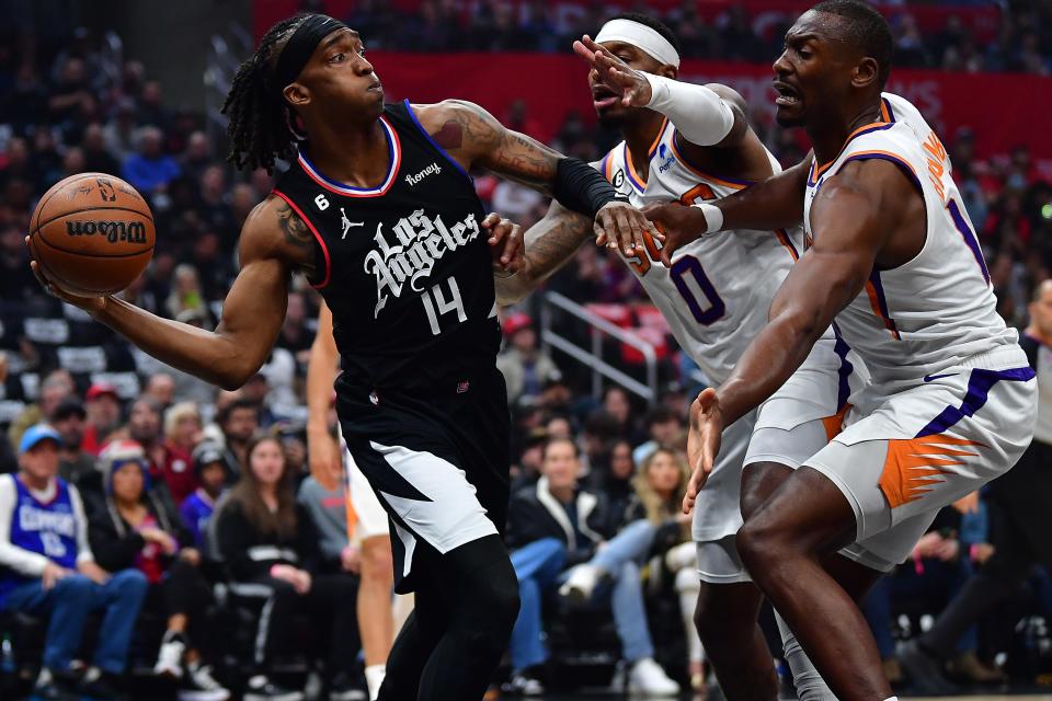 Dec 15, 2022; Los Angeles, California, USA; Los Angeles Clippers guard Terance Mann (14) passes the ball against Phoenix Suns forward Torrey Craig (0) and center Bismack Biyombo (18) during the first half at Crypto.com Arena. Mandatory Credit: Gary A. Vasquez-USA TODAY Sports