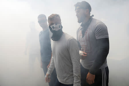 Demonstrators walk in a cloud of smoke after a brawl broke out during a Patriots Day Free Speech rally in Berkeley, California, U.S., April 15, 2017. REUTERS/Stephen Lam