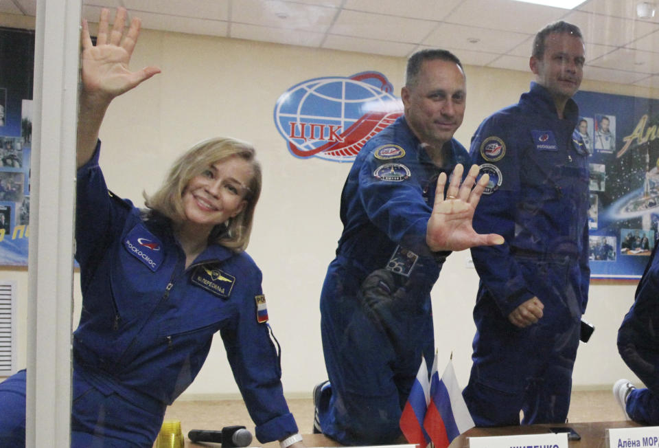 In this handout photo released by Roscosmos, actress Yulia Peresild, left, director Klim Shipenko, right, and cosmonaut Anton Shkaplerov, members of the prime crew of Soyuz MS-19 spaceship gesture after a news conference at the Russian launch facility in the Baikonur Cosmodrome, Kazakhstan, Monday, Oct. 4, 2021. In a historic first, Russia is set to launch an actress and a film director to space to make a feature film in orbit. Actress Yulia Peresild and director Klim Shipenko are set to blast off Tuesday for the International Space Station in a Russian Soyuz spacecraft together with Anton Shkaplerov, a veteran of three space missions.(Roscosmos Space Agency via AP)