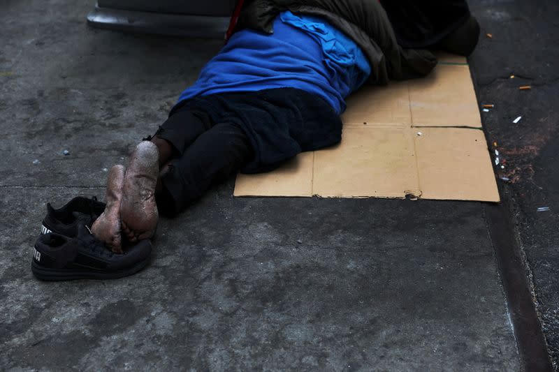 FILE PHOTO: A man sleeps on a cardboard box along 34th street near Pennsylvania Station in New York City,