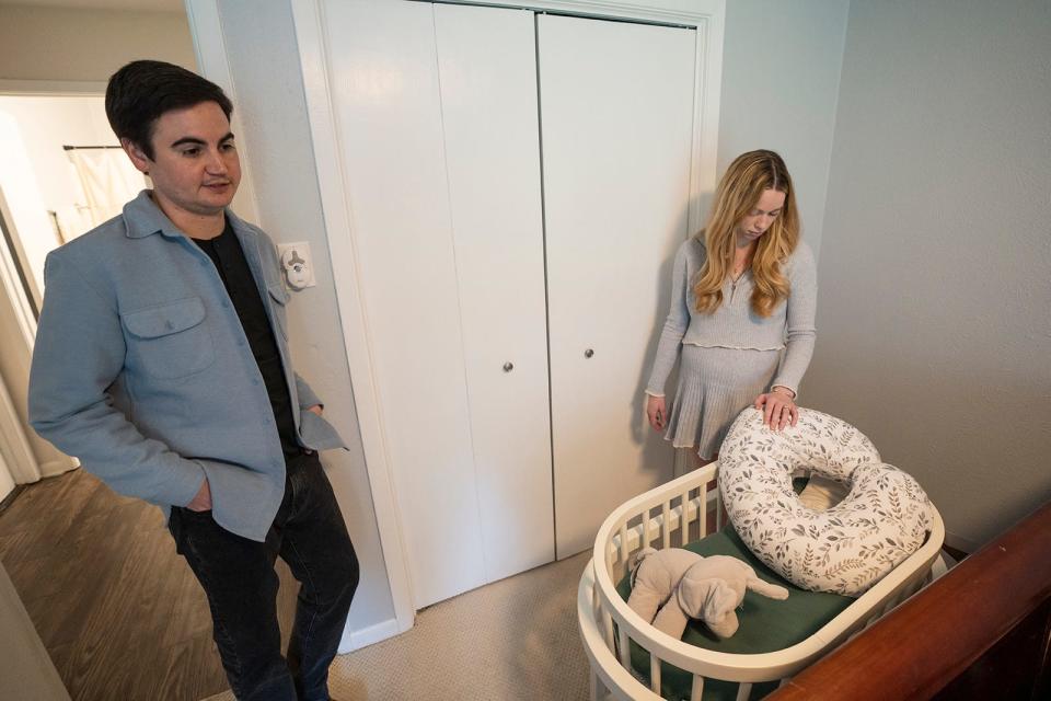 Travis and Taylor Edwards look over a bassinet and items for the baby from their current pregnancy at their home. Their first baby received a fatal diagnosis, prompting the couple to leave the state for an abortion. Alongside other plaintiffs, Taylor is suing the state, demanding medical exceptions for the procedure.