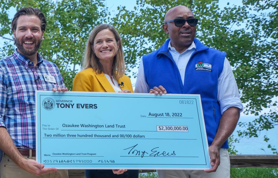 From left to right, Tom Stolp, executive director of Ozaukee-Washington Land Trust, State Rep. Deb Andraca and DNR Secretary Preston Cole hold a check for $2.3 million following a DNR news conference Thursday at Lion's Den Gorge Nature Preserve in Grafton.