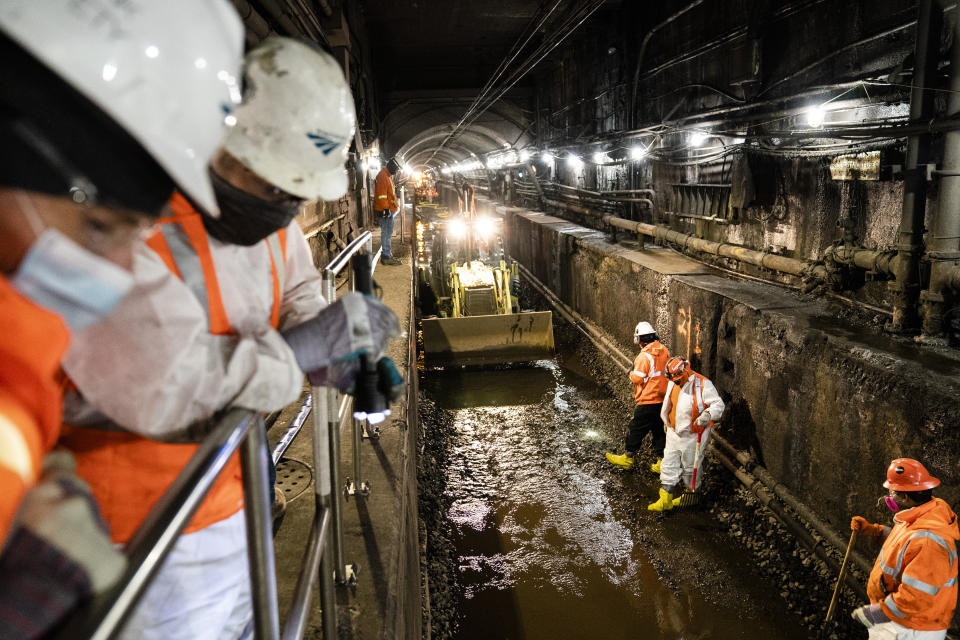 Amtrak workers perform tunnel repairs to a partially flooded train track bed, Saturday, March 20, 2021, in Weehawken, N.J. With a new rail tunnel into New York years away at best, Amtrak is embarking on an aggressive and expensive program to fix a 110-year-old tunnel in the interim. (AP Photo/John Minchillo)