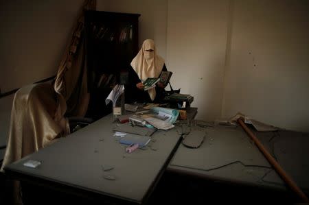 A Palestinian member of staff cleans her office at the Ministry of Religious Affairs that was damaged by Israeli air strikes in Gaza City, July 15, 2018. REUTERS/Suhaib Salem