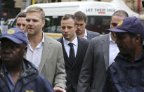 Oscar Pistorius, center rear, arrives at the high court for the third day of his trial in Pretoria, South Africa, Wednesday, March 5, 2014. Pistorius is charged with murder with premeditation in the shooting death of girlfriend Reeva Steenkamp in the pre-dawn hours of Valentine's Day 2013. (AP Photo/Schalk van Zuydam)