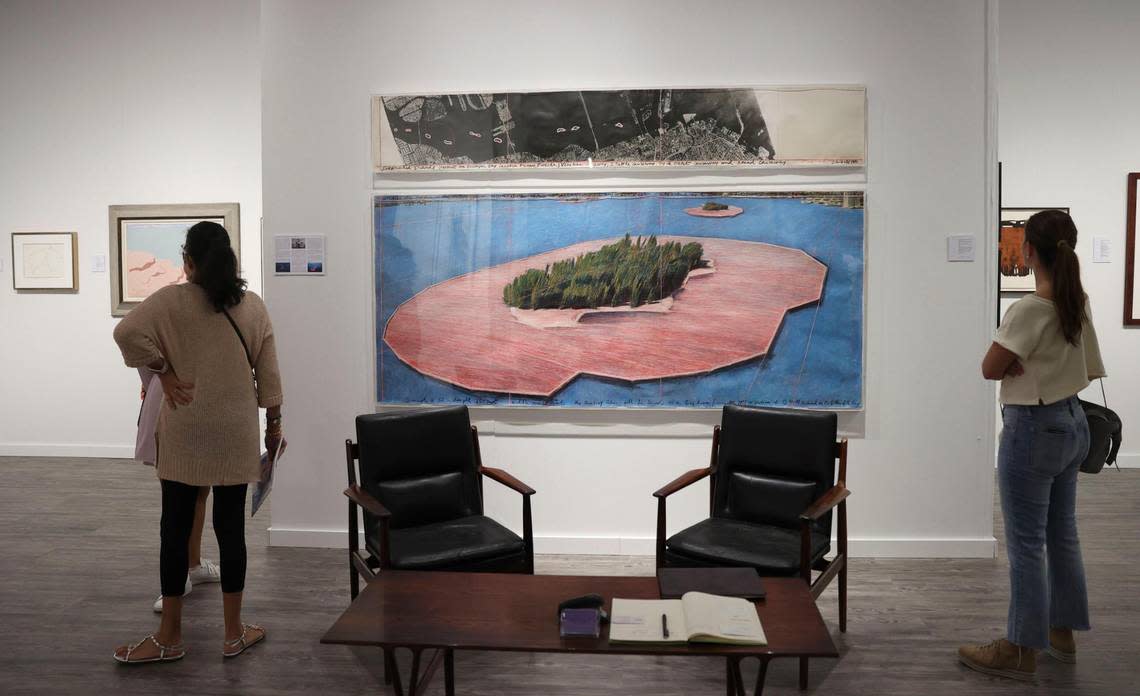 Two people admire ‘Surrounded Islands’ by Christo and Jeanne-Claude inside the Archeus/Post Modern gallery booth during the opening night of VIP for Art Miami.