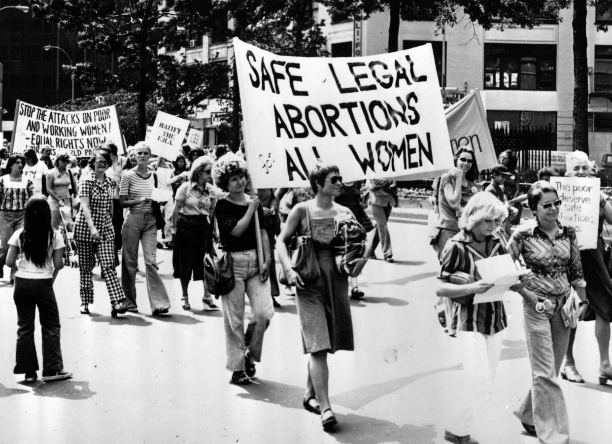 Historical photo of marchers carrying signs such as 