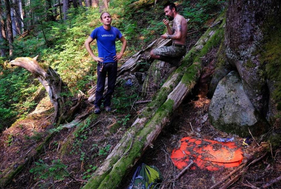 Kevin Dares, left, reacts after he found missing hiker Rachel Lakoduk’s sleeping pad and backpack, as Bud Carr radios another 49th Parallel member further down the mountain to send a satellite message to Lakoduk’s father Brad Tripp on Saturday, Aug. 14, 2021, near Marblemount, Wash. For Dares, whose girlfriend Sam Sayers went missing while hiking in 2018, finding Lakoduk brought on a wave of emotion. “Why can’t I find Sam?,” he said.