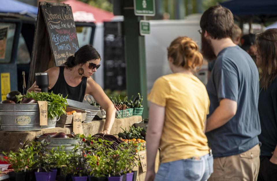 Sarah Dye organizes produce at the Schooner Creek Farm booth during an Aug. 17, 2019, session of the Bloomington Community Farmers’ Market next to City Hall.